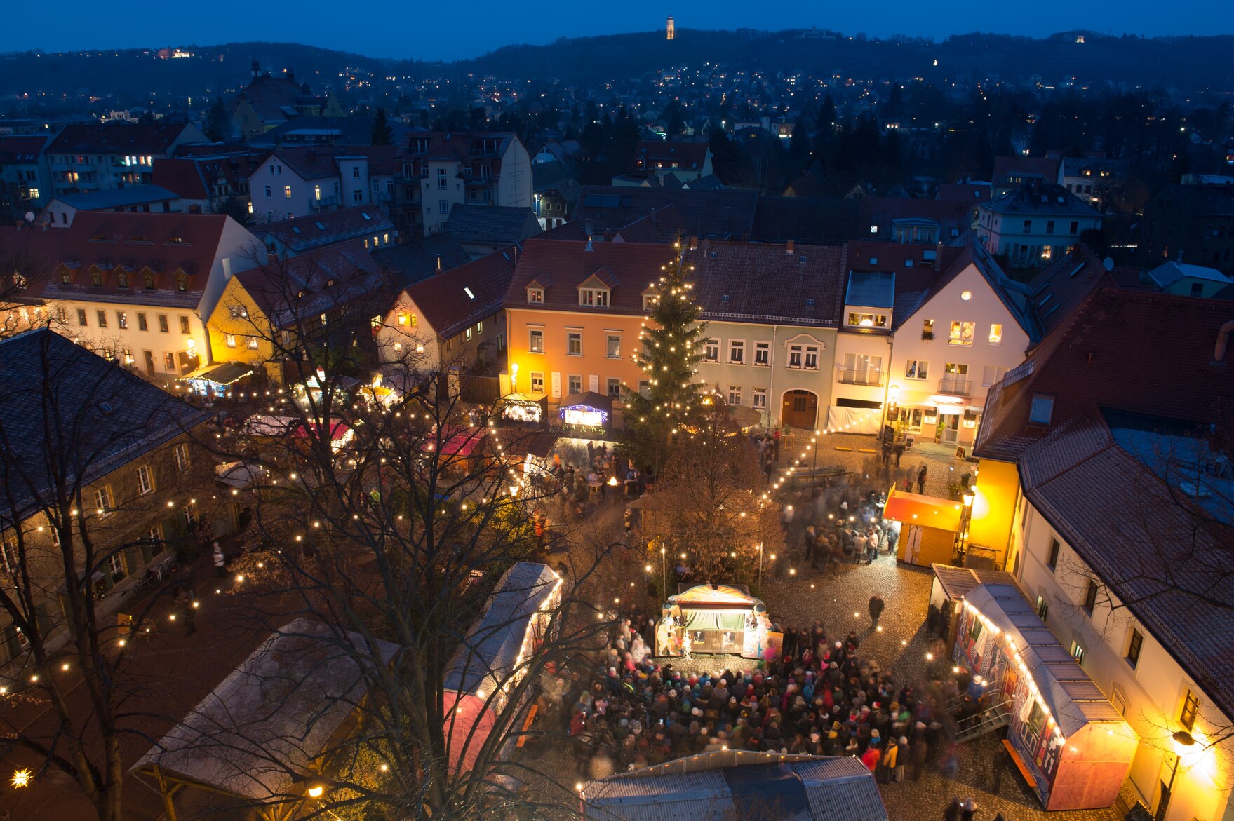 Ein Weihnachtsmarkt auf einem Marktplatz einer Stadt von oben